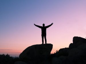 man on top of a mountain signifying success